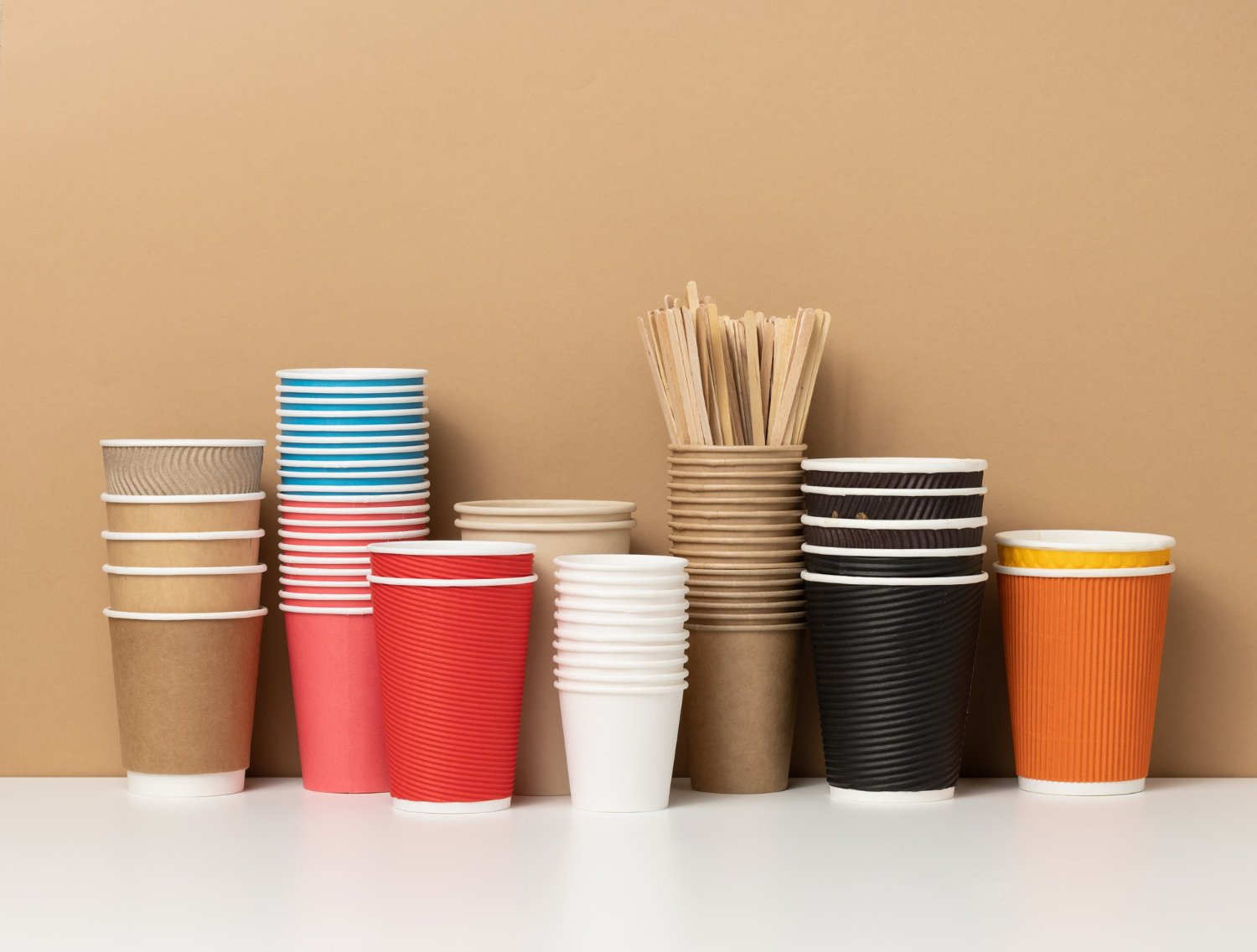 Stacks of colourful paper cups with wooden stirrers